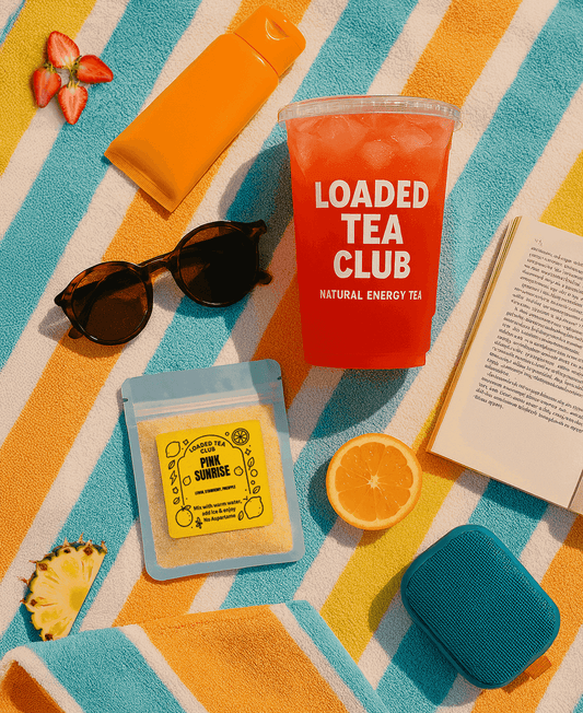 Bright summer setup featuring a loaded tea drink, sunglasses, tea packets, and fresh fruit on a colorful beach towel.
